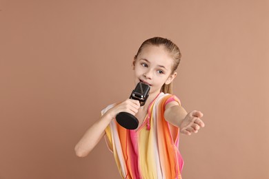 Photo of Little girl with microphone singing on light brown background