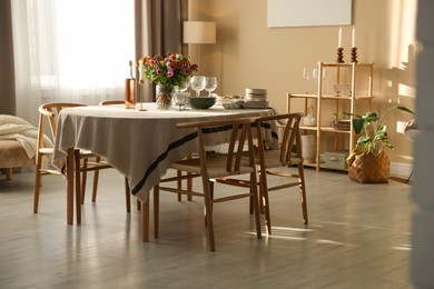 Photo of Stylish table setting with dishware, glasses and beautiful flowers indoors