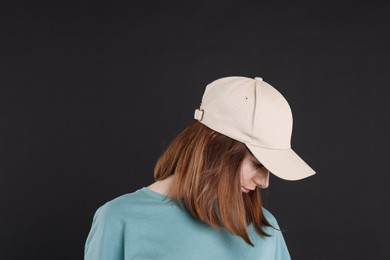 Photo of Woman in stylish baseball cap on black background. Mockup for design