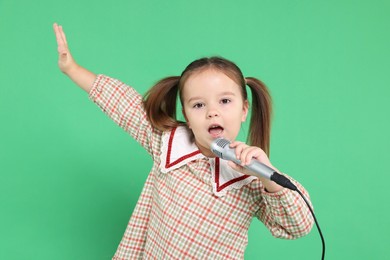 Photo of Cute girl with microphone singing on green background