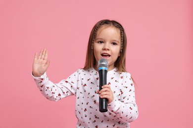 Photo of Cute girl with microphone singing on pink background