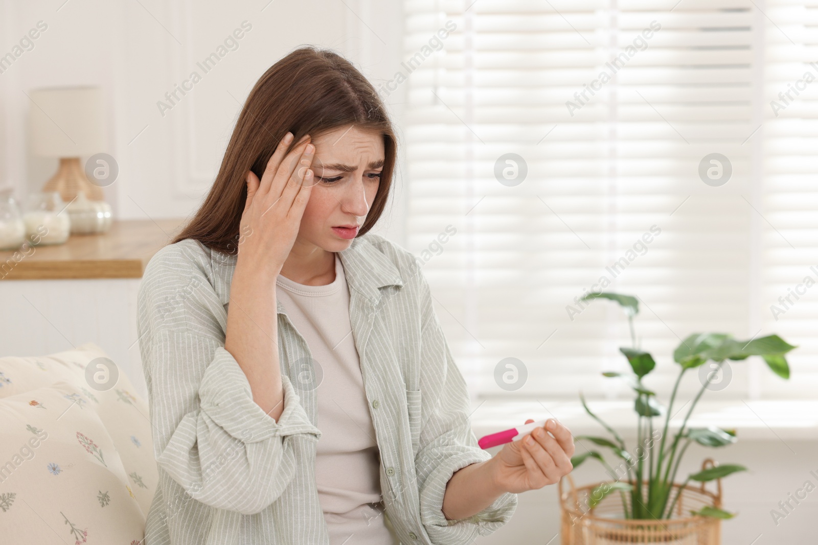 Photo of Upset woman with negative pregnancy test at home