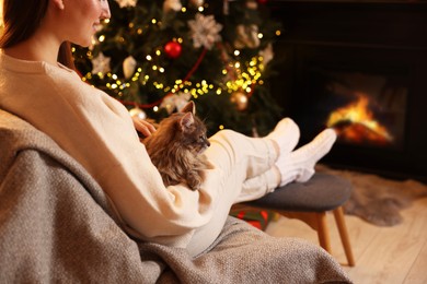 Photo of Woman with cute cat in room decorated for Christmas, closeup