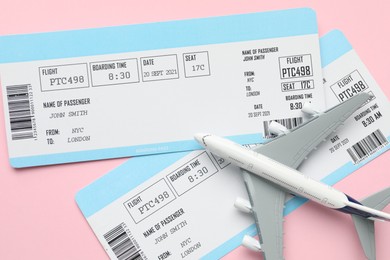 Photo of Travel agency. Flight tickets and plane model on pink background, flat lay