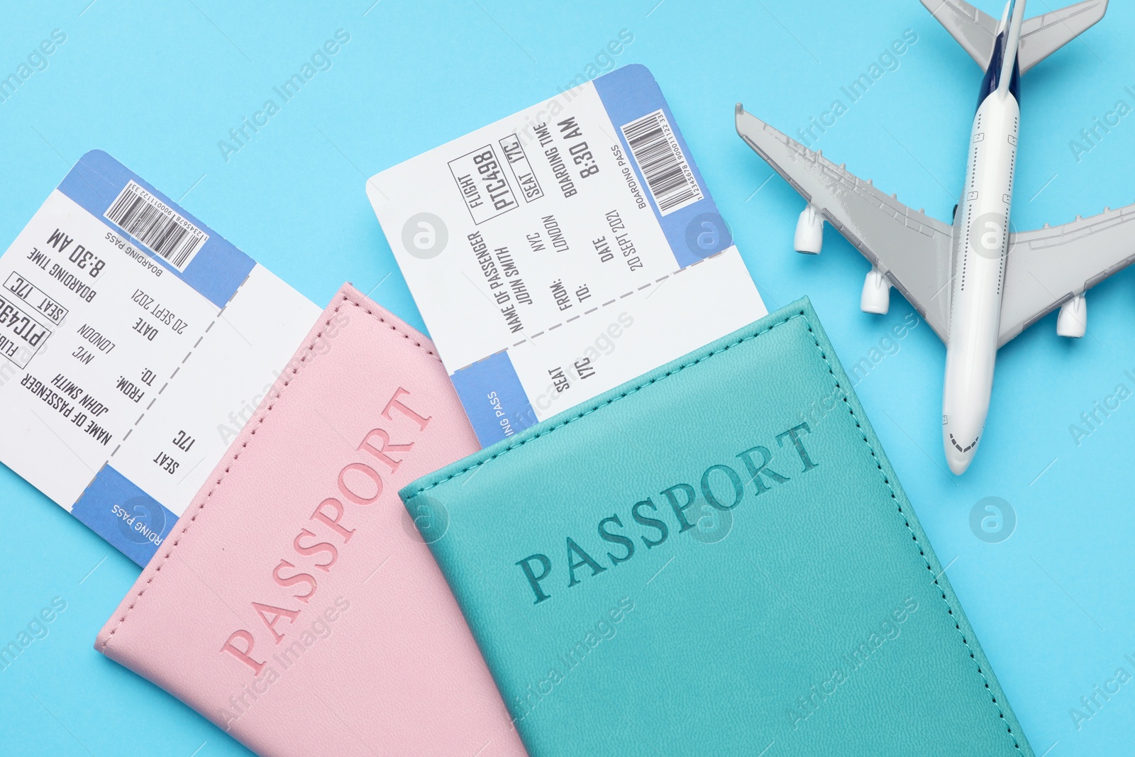 Photo of Travel agency. Flight tickets, passports and plane model on light blue background, top view