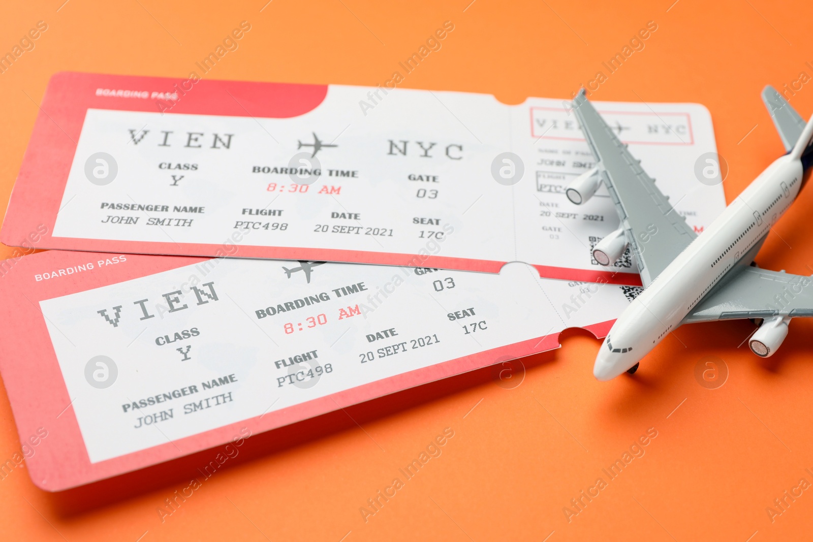 Photo of Travel agency. Flight tickets and plane model on orange background, closeup