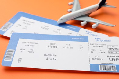 Photo of Travel agency. Flight tickets and plane model on orange background, closeup