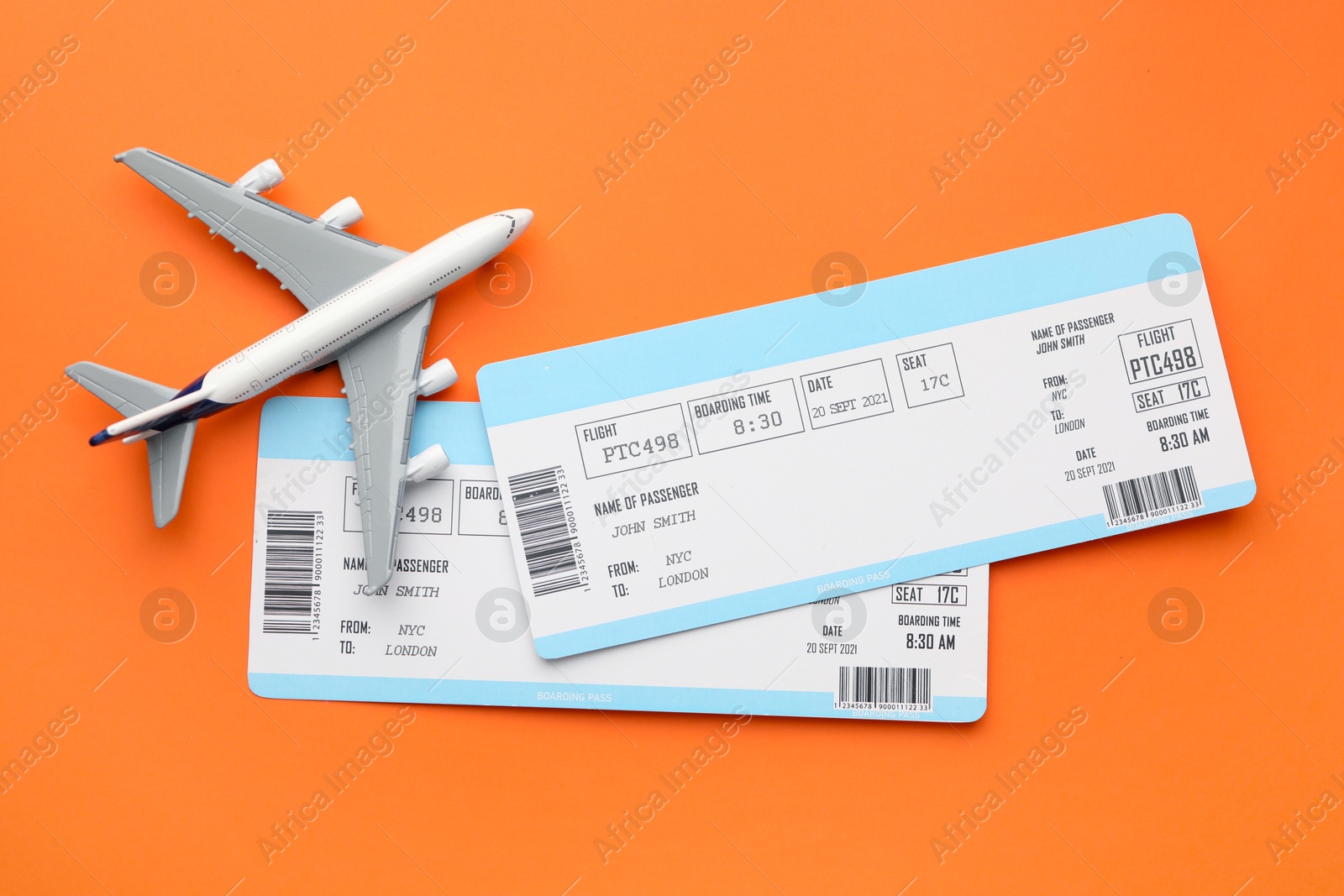 Photo of Travel agency. Flight tickets and plane model on orange background, flat lay