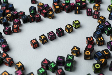 Photo of Word Racism and beads on light grey background, closeup