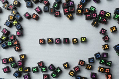 Photo of Word Racism and beads on light grey background, flat lay