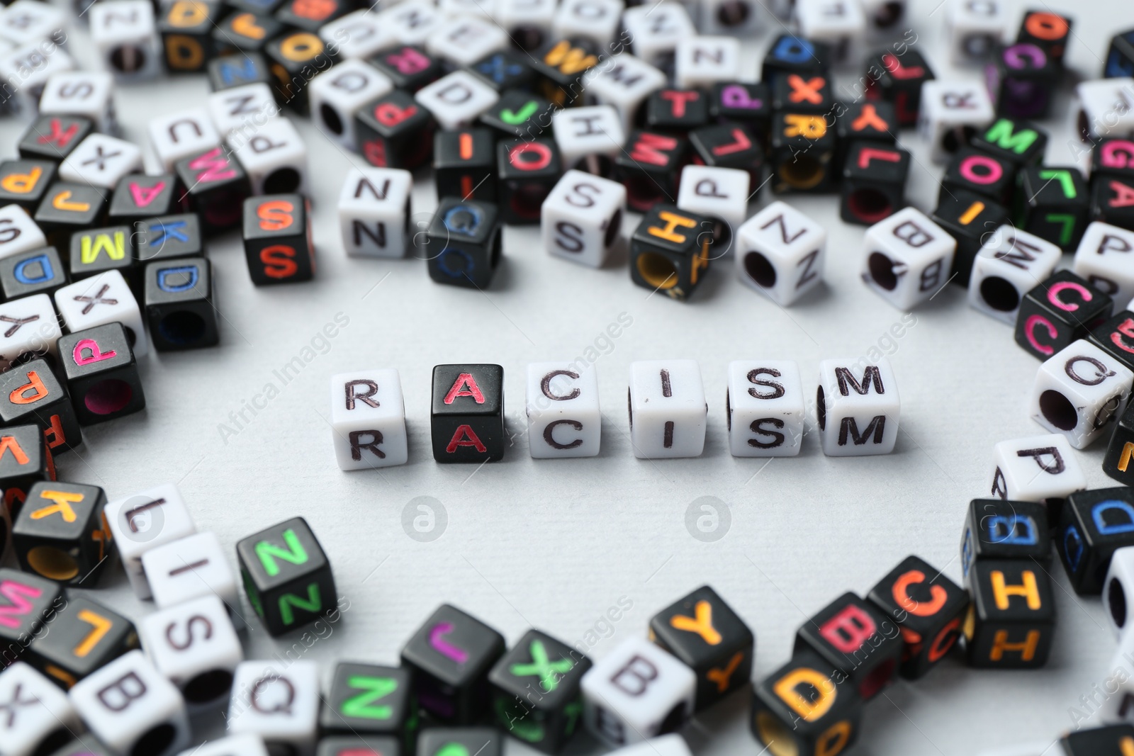 Photo of Word Racism and beads on light grey background, closeup