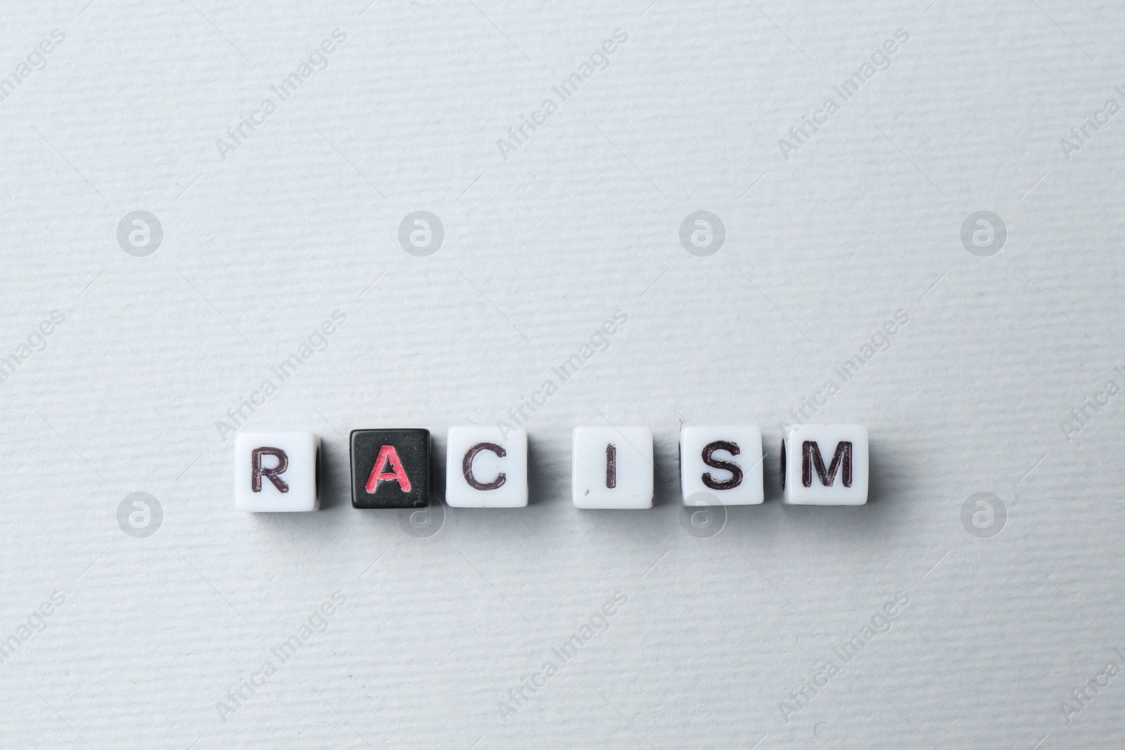 Photo of Word Racism made with beads on light grey background, top view