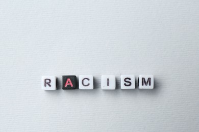 Photo of Word Racism made with beads on light grey background, top view