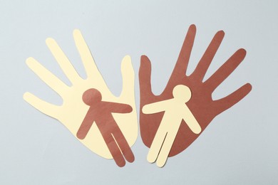 Photo of Stop racism. Hands and human paper figures of different colors on light grey background, top view