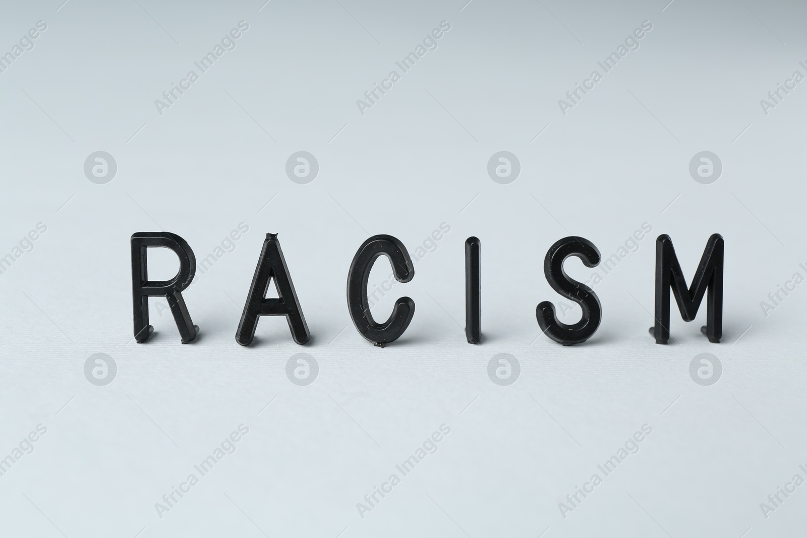 Photo of Word Racism on light grey background, closeup