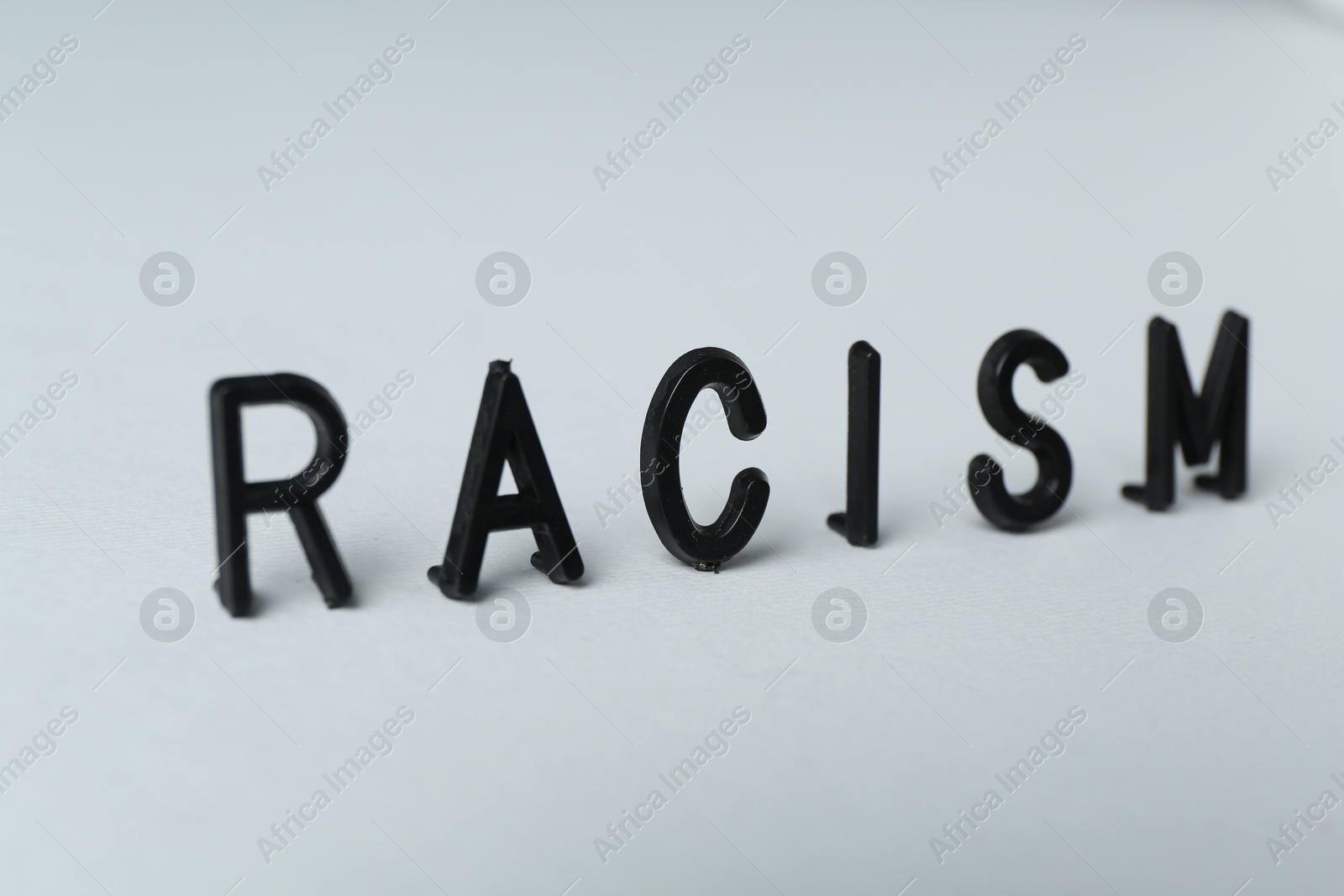 Photo of Word Racism on light grey background, closeup