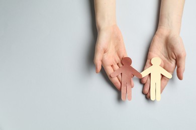 Photo of Stop racism. Woman holding human paper figures of different colors on light grey background, top view. Space for text