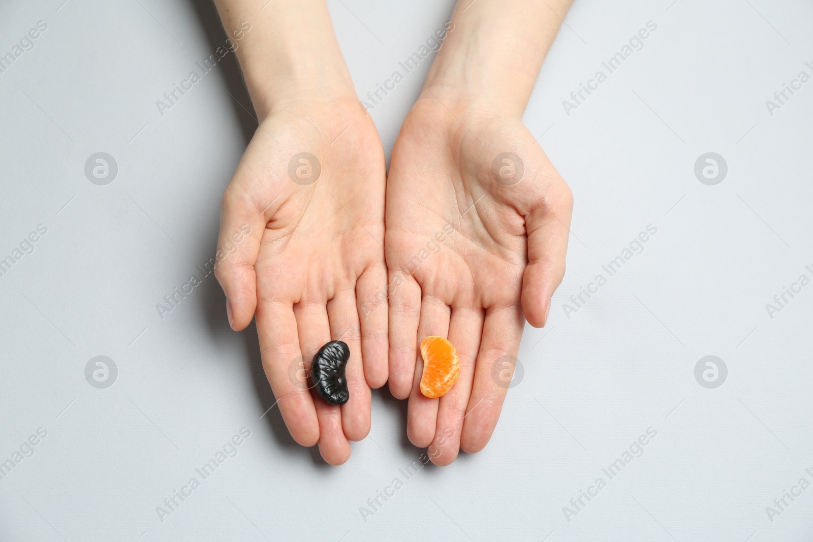 Photo of Woman with tangerine segments of different colors on light grey background, top view