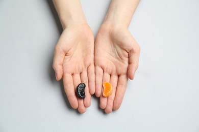 Photo of Woman with tangerine segments of different colors on light grey background, top view