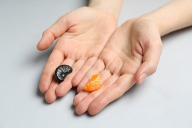 Photo of Woman with tangerine segments of different colors on light grey background, closeup