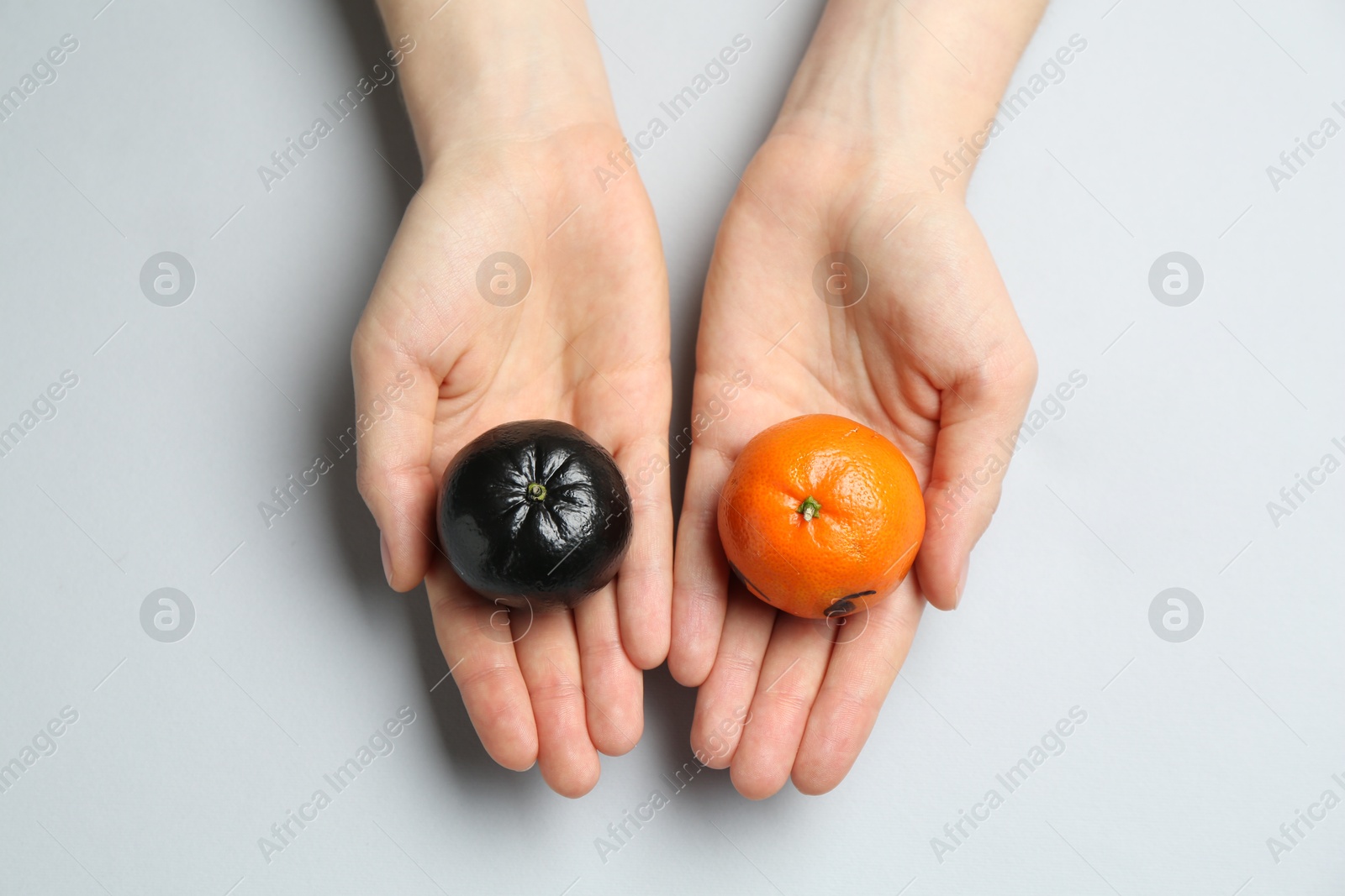 Photo of Woman with tangerines of different colors on light grey background, top view