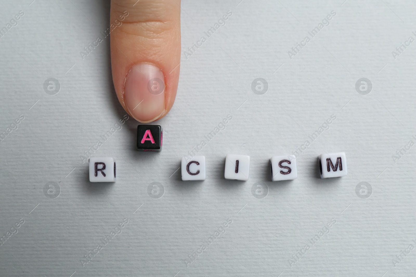 Photo of Woman with word Racism on light grey background, top view