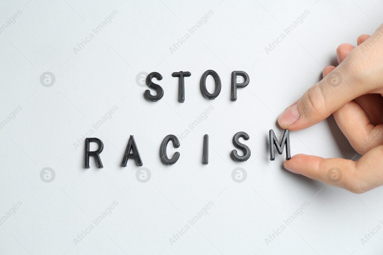 Photo of Woman with phrase Stop Racism on light grey background, top view