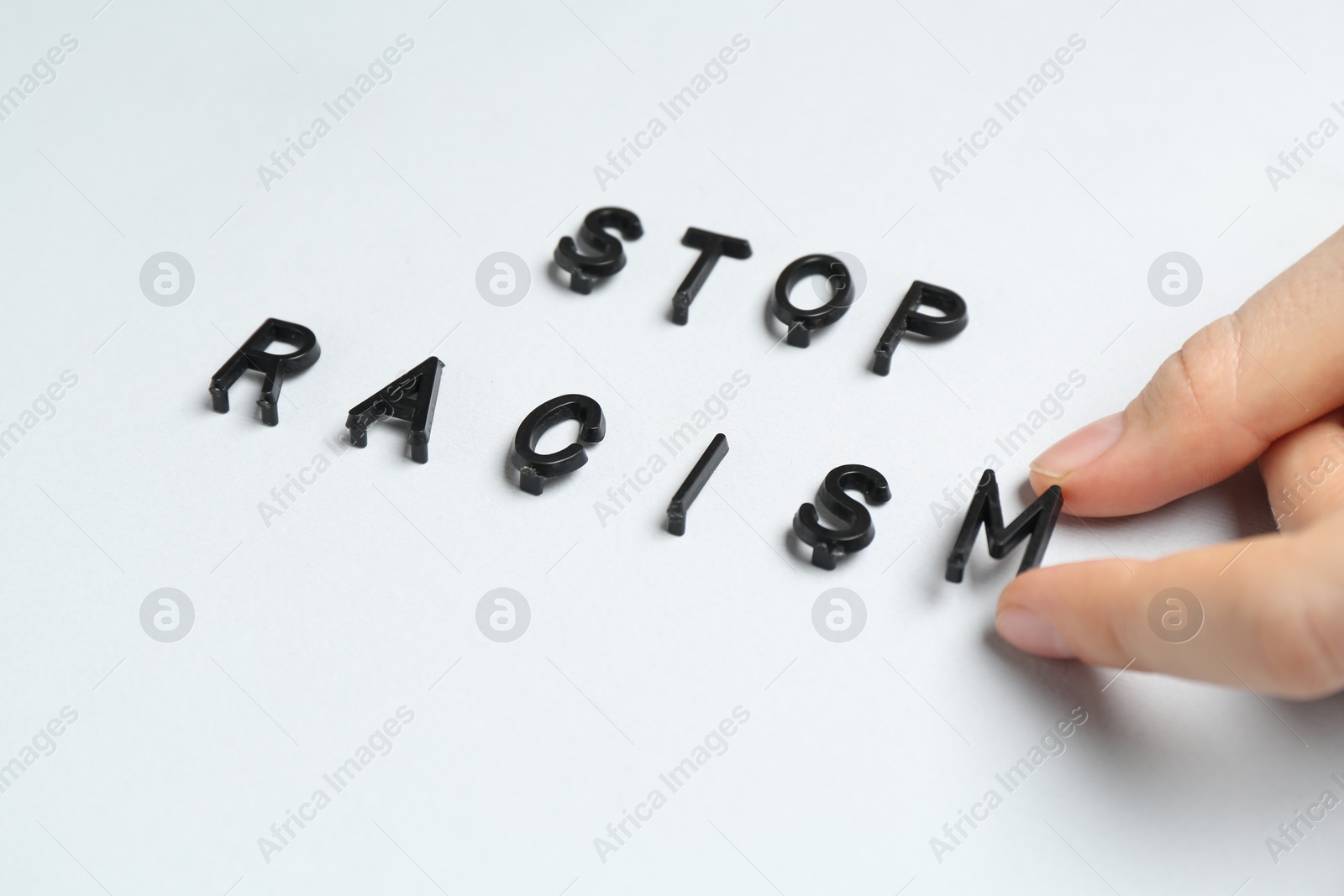 Photo of Woman with phrase Stop Racism on light grey background, closeup