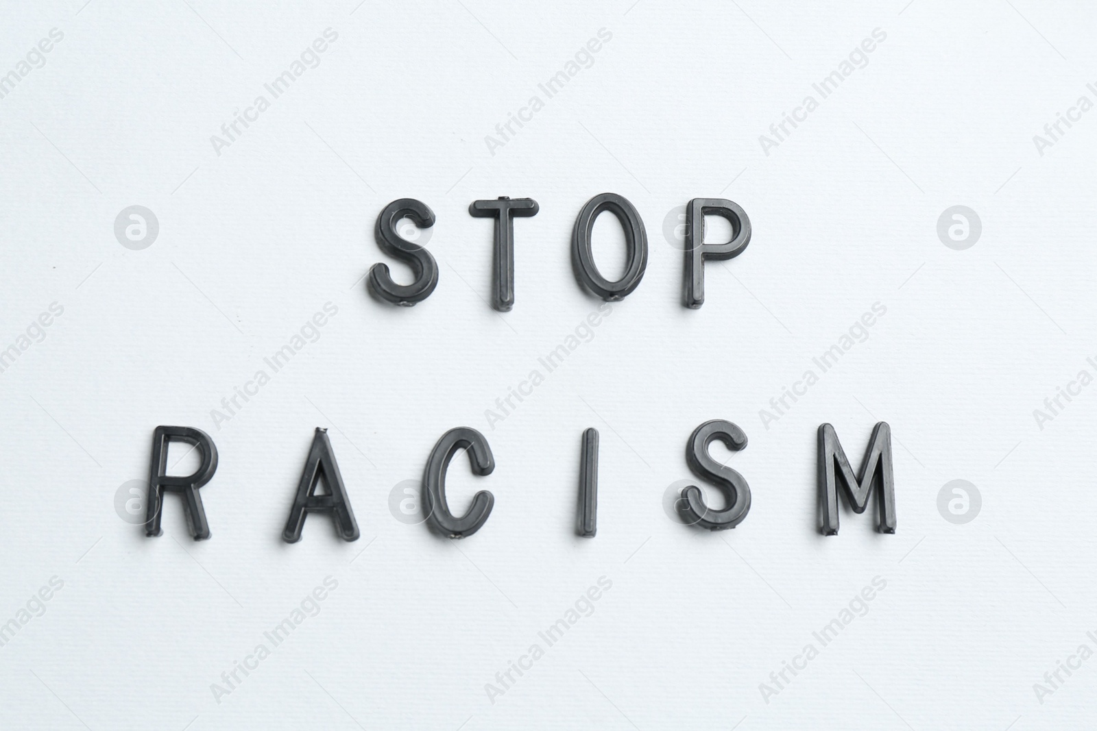 Photo of Phrase Stop Racism on light grey background, top view