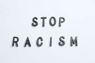 Photo of Phrase Stop Racism on light grey background, top view