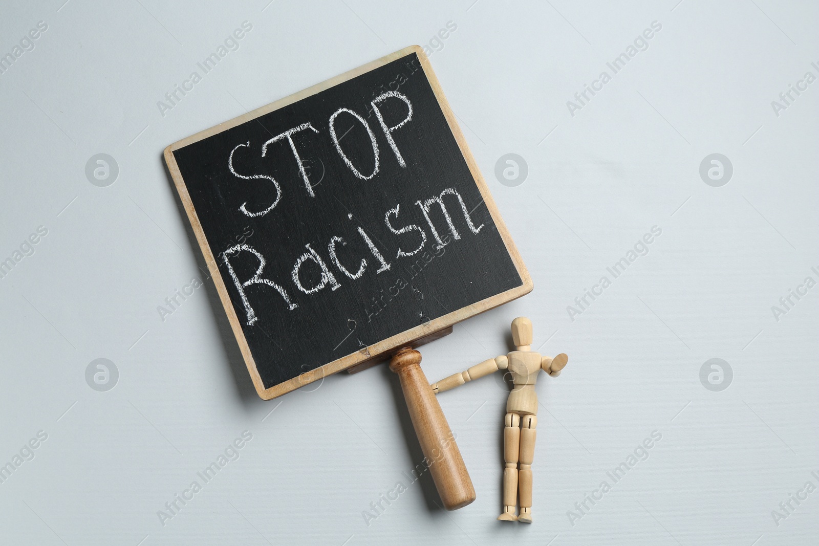 Photo of Chalkboard with phrase Stop Racism and human figure on light grey background, top view