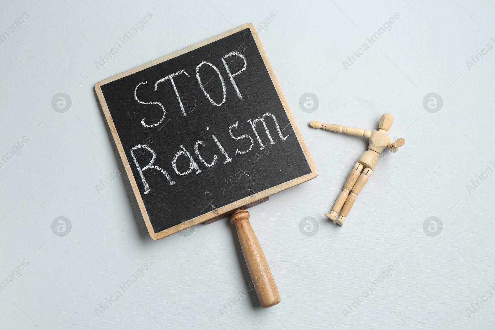 Photo of Chalkboard with phrase Stop Racism and human figure on light grey background, top view