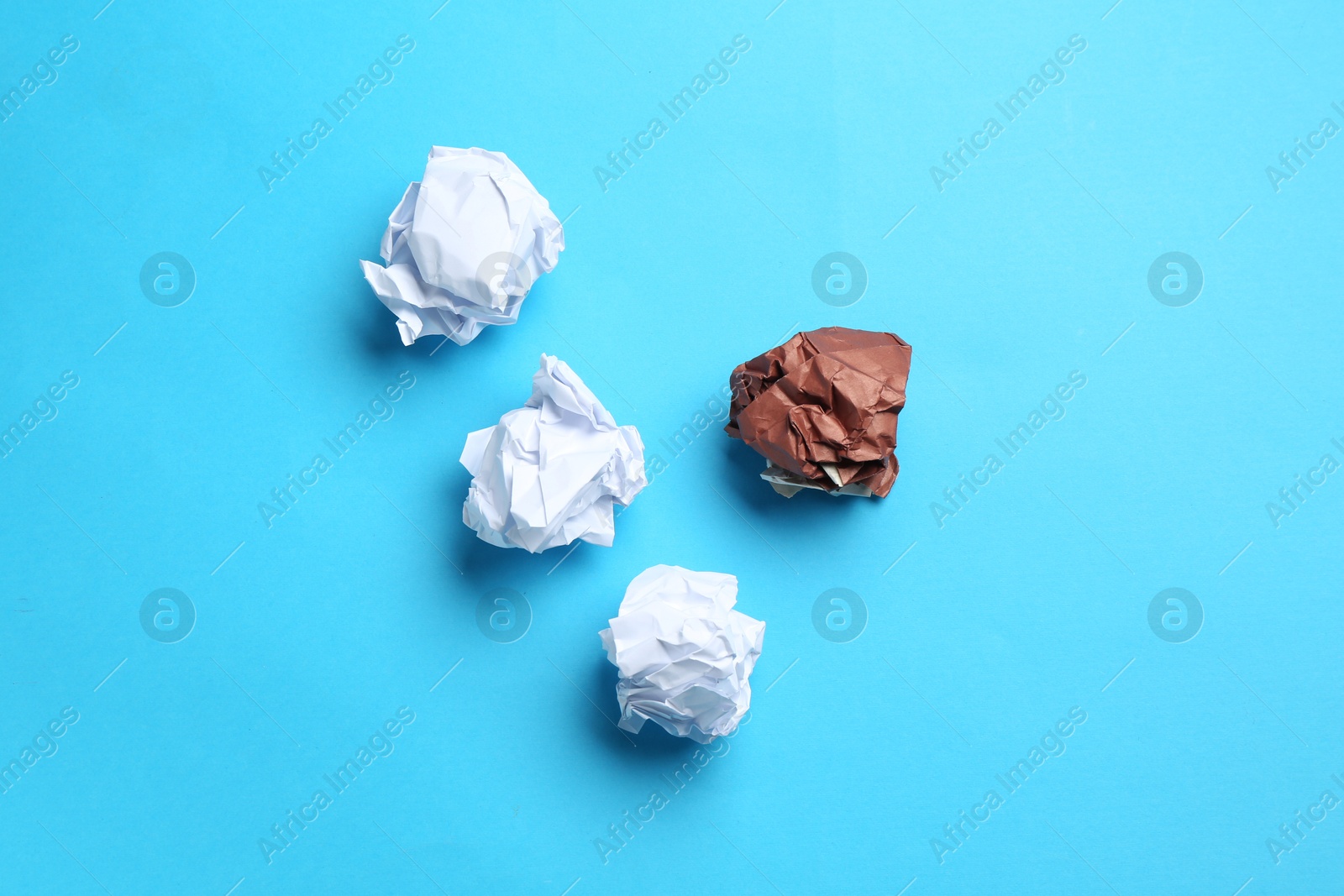 Photo of Stop racism. Crumpled paper pieces of different colors on light blue background, flat lay