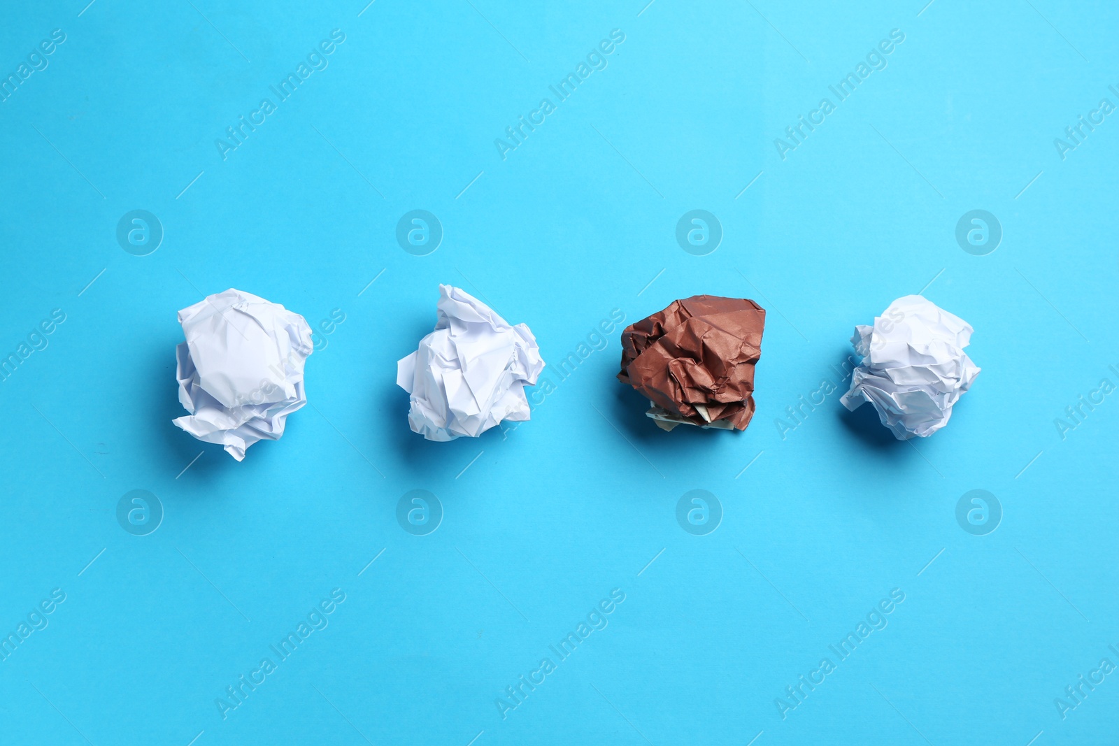 Photo of Stop racism. Crumpled paper pieces of different colors on light blue background, flat lay