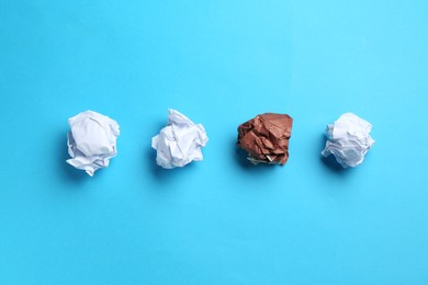 Photo of Stop racism. Crumpled paper pieces of different colors on light blue background, flat lay