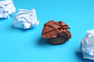 Photo of Stop racism. Crumpled paper pieces of different colors on light blue background, closeup