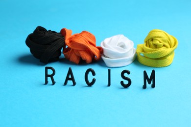 Word Racism and shoelaces of different colors on light blue background