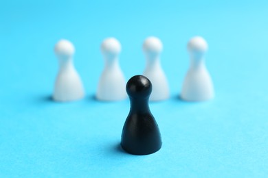 Photo of Stop racism. One black human figure among white ones on light blue background, closeup