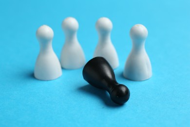 Photo of Stop racism. One black human figure among white ones on light blue background, closeup