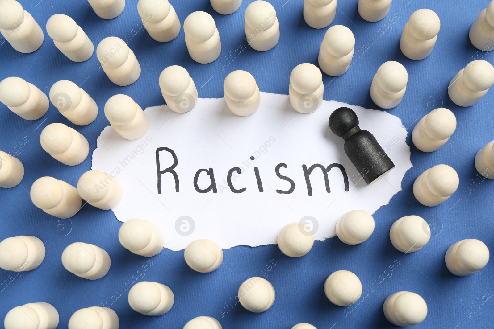 Photo of Card with word Racism and human figures of different colors on blue background, flat lay