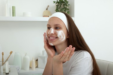 Photo of Teenage girl with cleansing foam on her face at home. Acne treatment