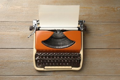 Photo of Vintage typewriter with sheet of paper on wooden table, top view
