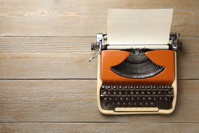Photo of Vintage typewriter with sheet of paper on wooden table, top view. Space for text