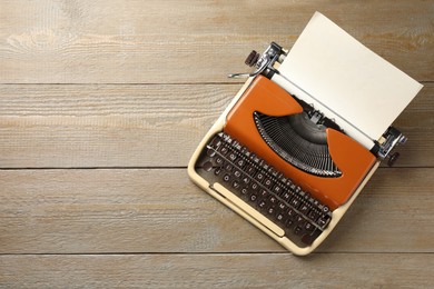 Photo of Vintage typewriter with sheet of paper on wooden table, top view. Space for text