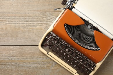 Photo of Vintage typewriter with sheet of paper on wooden table, top view. Space for text