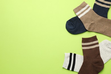 Photo of Different comfortable socks on light green background, flat lay. Space for text