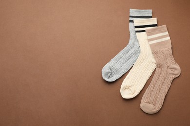 Photo of Different comfortable socks on brown background, flat lay. Space for text