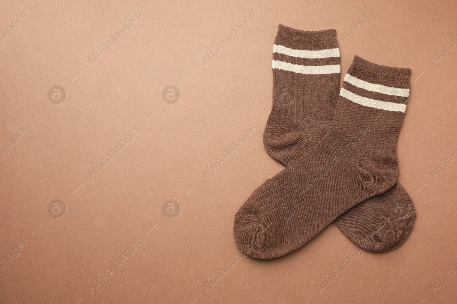 Photo of Pair of soft comfortable socks on brown background, top view. Space for text