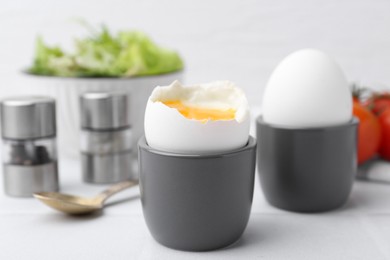 Photo of Soft boiled eggs in cups served on white table, closeup