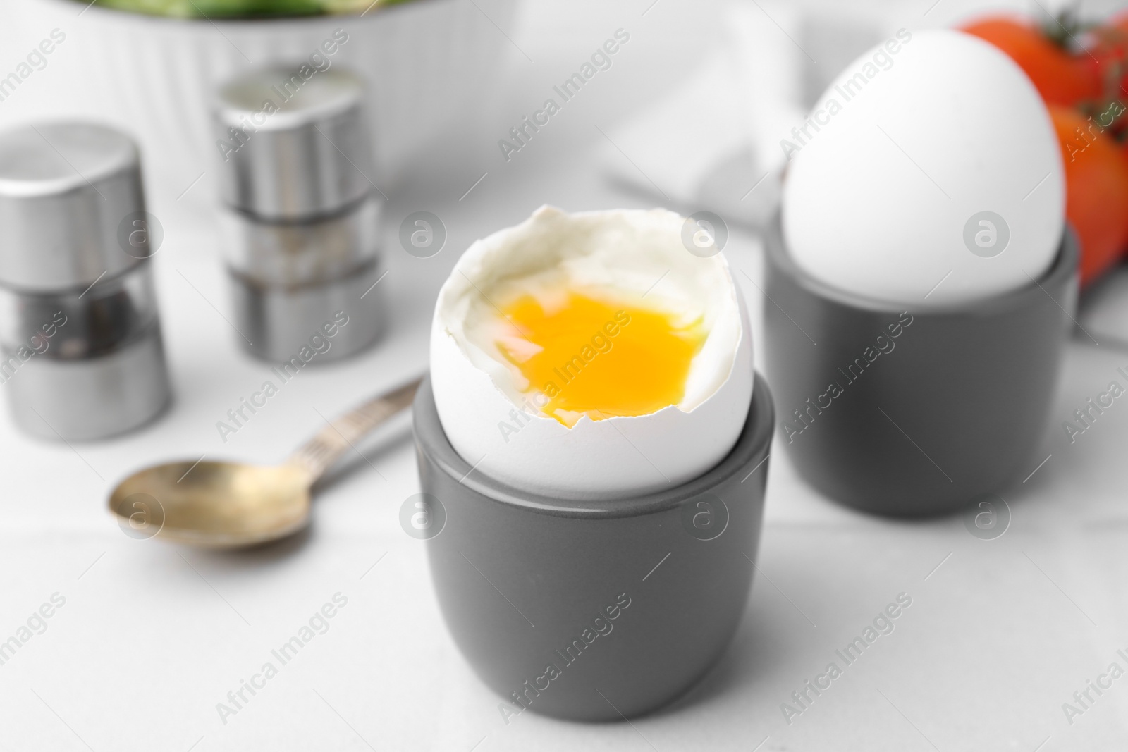 Photo of Soft boiled eggs in cups served on white table, closeup